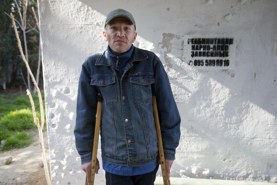 In this photo taken Tuesday, April 1, 2014, Roman, a patient of treatment for drug addiction, poses at a bus stop with an advert reading "Rehabilitation of drug and alcohol addicts" in Sevastopol, Crimea. Across the Black Sea peninsula, some 800 heroin addicts and other needle-drug users take part in methadone programs, seen as an important part of efforts to curb HIV infections by taking the patients away from hypodermic needles that can spread the AIDS-causing virus. After Russia's annexation of Crimea methadone was banned. The ban could undermine years of efforts to reduce the spread of AIDS in Crimea. (AP Photo/Pavel Golovkin)