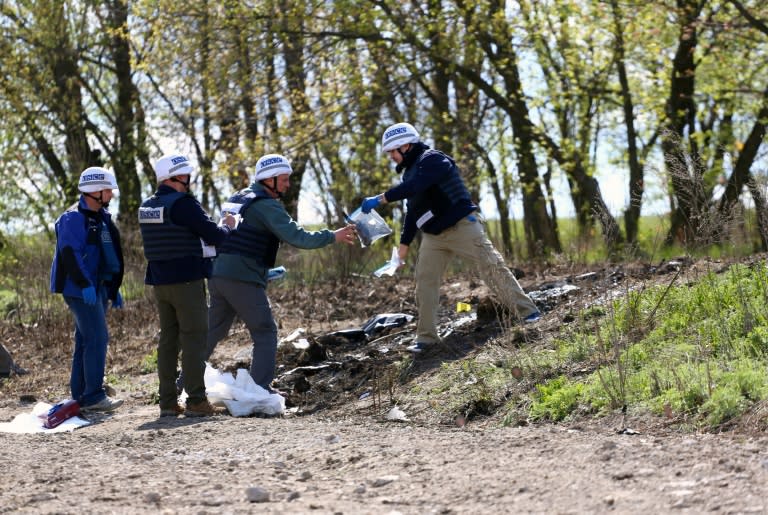 OSCE monitors inspect the site near the Ukrainian village of Pryshyb, near Lugansk, on April 25, 2017, where an OSCE patrol vehicle was destroyed by an explosion on April 23