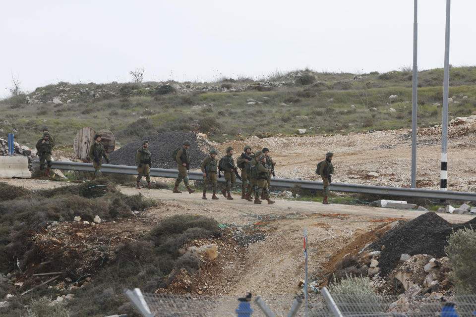 Israeli soldiers deeply near the scene of an attack near the settlement of Givat Assaf in the West Bank, Thursday, Dec. 13, 2018. A Palestinian gunman opened fire at a bus stop outside a West Bank settlement on Thursday, shooting at soldiers and civilians and killing at least two Israelis before fleeing, the military and Israel's rescue service said. (AP Photo/Nasser Shiyoukhi)