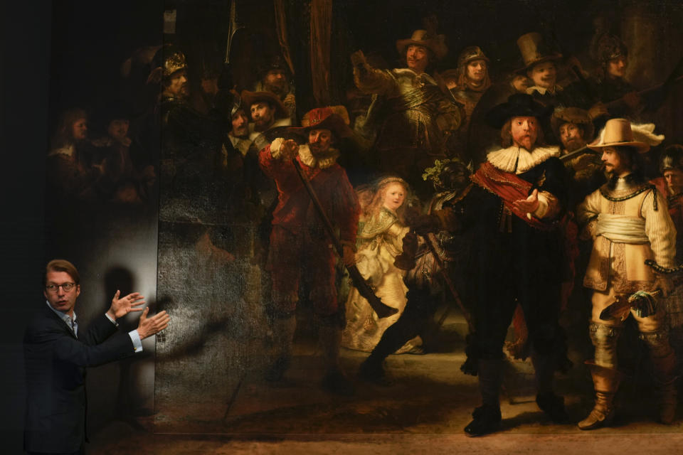 Museum director Taco Dibbits explains how Rembrandt's biggest painting the Night Watch just got bigger with the help of artificial intelligence in Amsterdam, Netherlands, Wednesday, June 23, 2021. Right above Dibbits, left, one of the added parts is seen, the Dutch national museum and art gallery reveals findings from a long-term project to examine in minute detail Rembrandt van Rijn's masterpiece the Night Watch. (AP Photo/Peter Dejong)