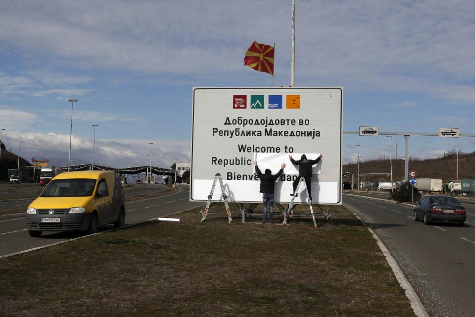 Workers replace signage with an adhesive banner in the southern border with Greece, near Gevgelija, North Macedonia, Wednesday, Feb. 13, 2019. Workers in the newly renamed North Macedonia have begun replacing road signs to reflect the change in their country's name, following a deal with neighboring Greece to end a nearly three decade-long dispute and secure NATO membership. (AP Photo/Boris Grdanoski)