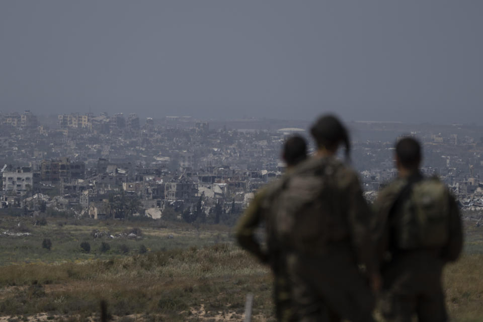 Israeli soldiers look at destroyed buildings in the Gaza Strip as they stand near the Israeli-Gaza border, as seen from southern Israel, Tuesday, April 9, 2024. (AP Photo/Leo Correa)