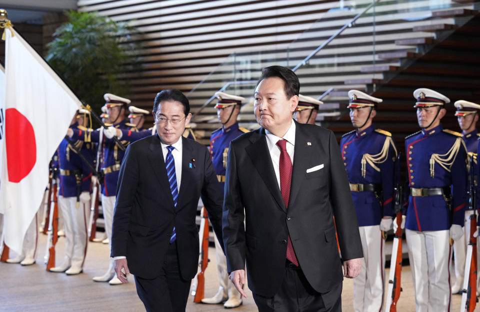 South Korean President Yoon Suk Yeol, center, and Japanese Prime Minister Fumio Kishida, left, attend an honor guard ceremony, ahead of their bilateral meeting at the Prime Minister's Office, in Tokyo, Japan, Thursday, March 16, 2023. (Franck Robichon/Pool Photo via AP)