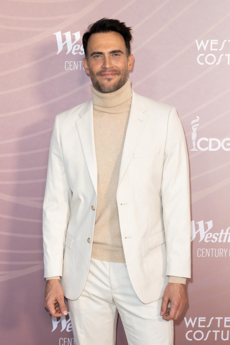 Cheyenne in a beige turtleneck and white suit at a film event