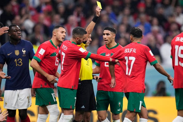 Referee Cesar Ramos, of Mexico, shows a yellow card to Morocco’s Sofiane Boufal