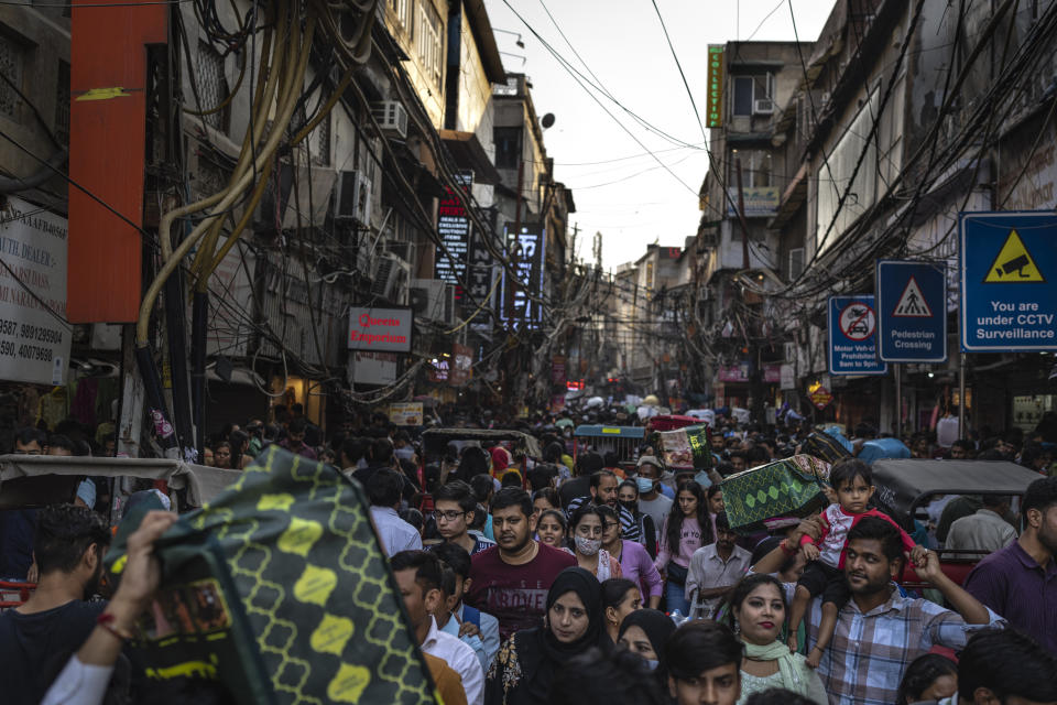 Shoppers crowd a market in New Delhi, India, Saturday, Nov. 12, 2022. The 8 billionth baby on Earth is about to be born on a planet that is getting hotter. But experts in climate science and population both say the two issues aren't quite as connected as they seem. (AP Photo/Altaf Qadri)