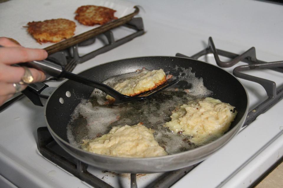 Flipping latkes in a frying pan.