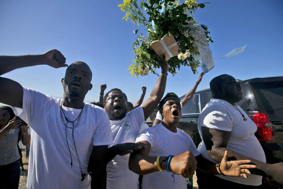 Anti-government protesters shout slogans as they are going to place flowers at Titanyen, a mass burial site, during a memorial service honoring the victims of the 2010 earthquake in Port-au-Prince, Haiti, Sunday, Jan. 12, 2020. Sunday marks the 10th anniversary of the devastating 7.0 magnitude earthquake that destroyed an estimated 100,000 homes across the capital and southern Haiti, including some of the country's most iconic structures. (AP Photo/Dieu Nalio Chery)