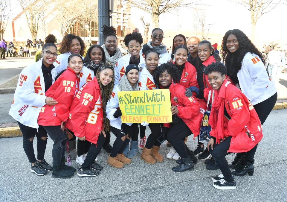 A group of young African American women hold a sign that reads #StandWithBennet