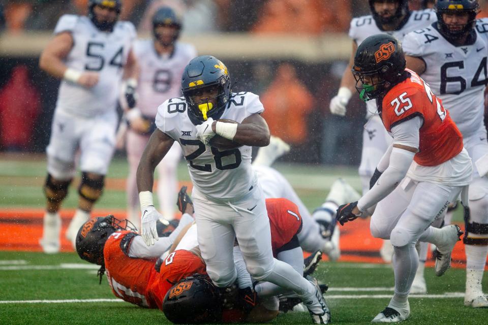 Oklahoma State linebacker Mason Cobb (0), linebacker Xavier Benson (1), and cornerback Cam Smith (3) tackle West Virginia's Jaylen Anderson (28) during the second half of the NCAA college football game in Stillwater, Okla., Saturday Nov. 26, 2022. (AP Photo/Mitch Alcala)