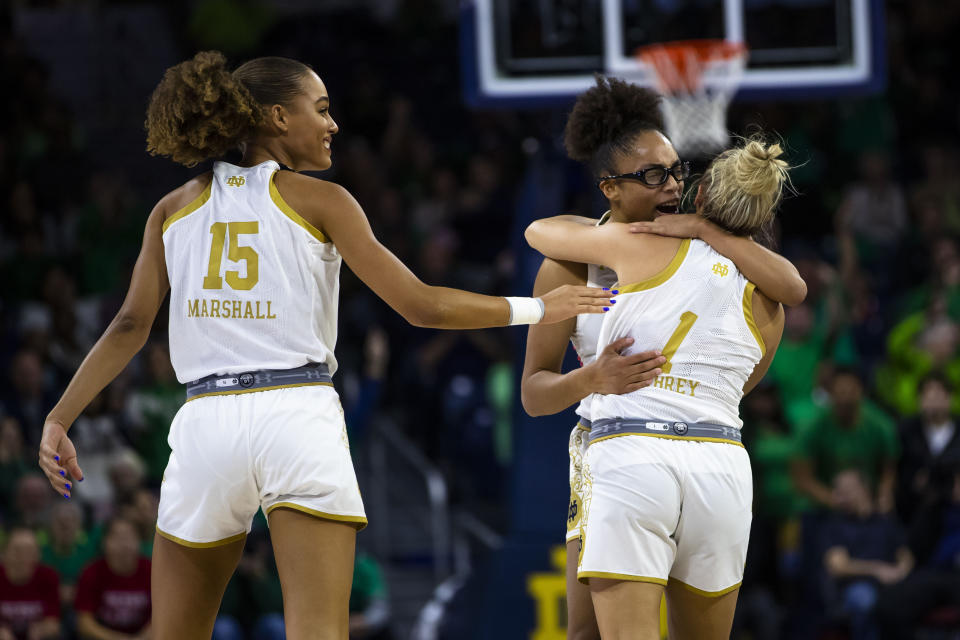 Notre Dame's Olivia Miles, center, hugs Dara Mabrey (1) as Natalija Marshall (15) smiles during the first half of an NCAA college basketball game against Connecticut on Sunday, Dec. 4, 2022, in South Bend, Ind. (AP Photo/Michael Caterina)