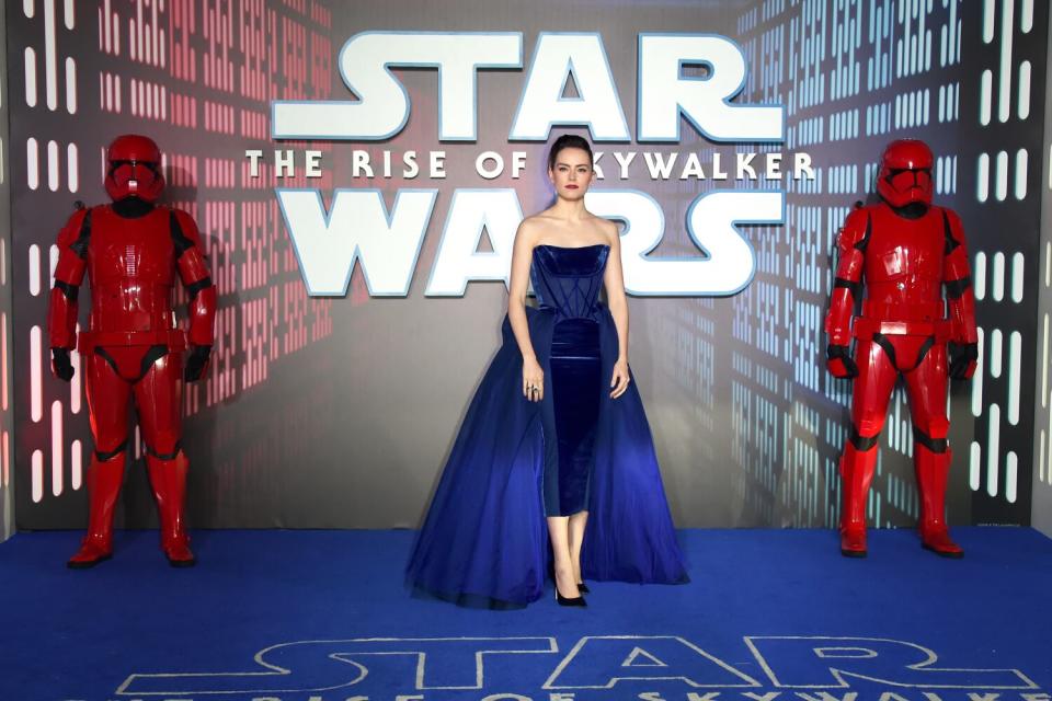 A dark-haired woman in a blue bodice dress in front of a Star Wars sign.