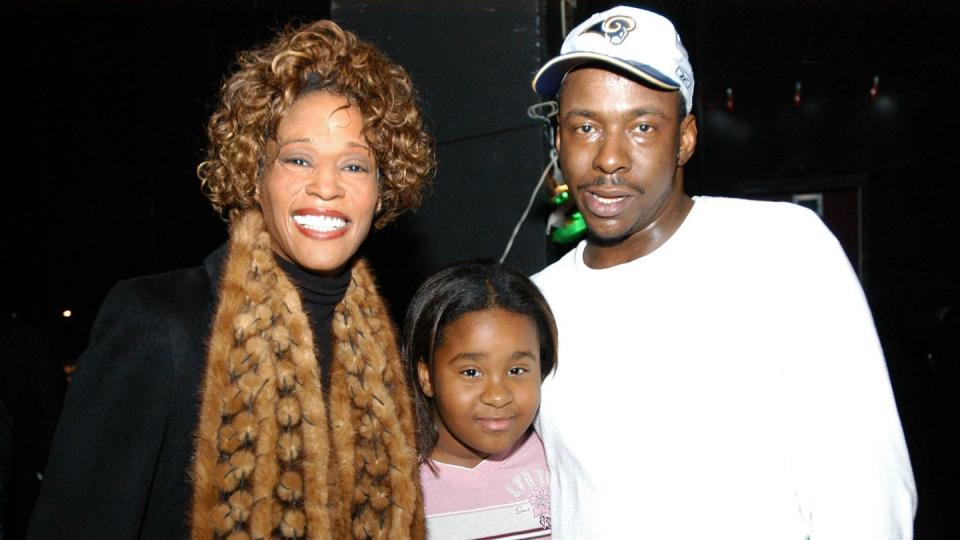 whitney houston, bobbi kristina brown, and bobby brown stand together and smile for a photo,