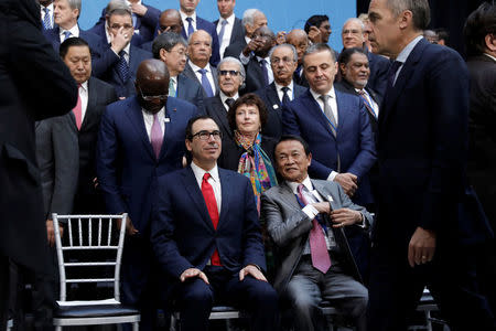 U.S. Treasury Secretary Steve Mnuchin (C) and Japan's Deputy Prime Minister and Finance Minister Taro Aso look on as Bank of England Governor Mark Carney arrives at the IMFC family photo during the IMF/World Bank spring meeting in Washington, U.S., April 21, 2018. REUTERS/Yuri Gripas