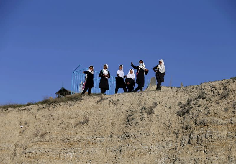 FILE PHOTO: School girls walk on a hilltop as they head home in Kabul