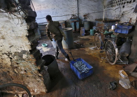 A worker pulls a basket filled with auto parts inside a workshop in Faridabad, December 24, 2015. REUTERS/Adnan Abidi/Files