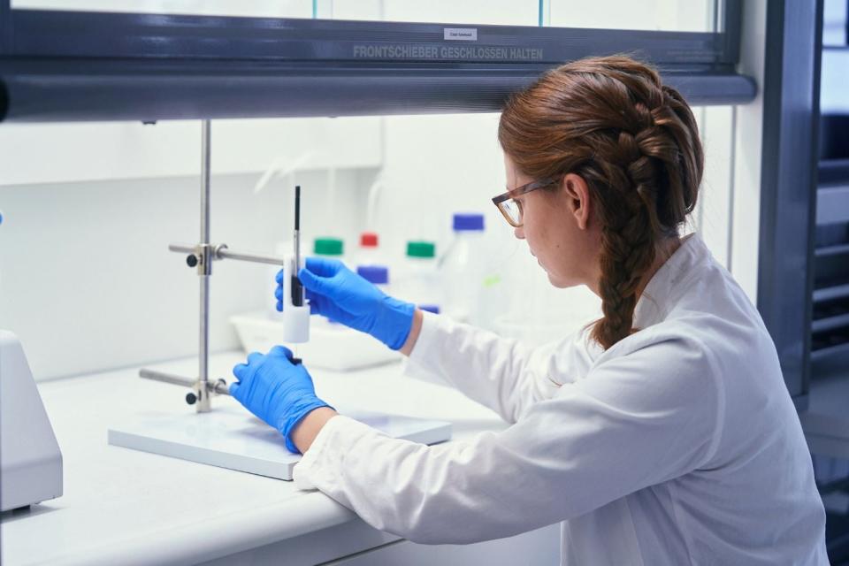 A scientist works under a fume hood.