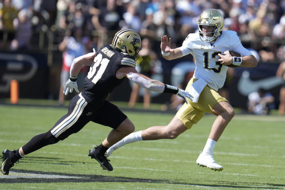 Notre Dame quarterback Riley Leonard (13) tries to get around Purdue defensive back Dillon Thieneman (31) during the first half of an NCAA college football game in West Lafayette, Ind., Saturday, Sept. 14, 2024. (AP Photo/Michael Conroy)