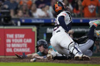 Seattle Mariners' Dylan Moore, left, scores the tying run past Houston Astros catcher Yainer Diaz, top, on a hit by Luis Urías during the eighth inning of a baseball game Sunday, May 5, 2024, in Houston. (AP Photo/Kevin M. Cox)