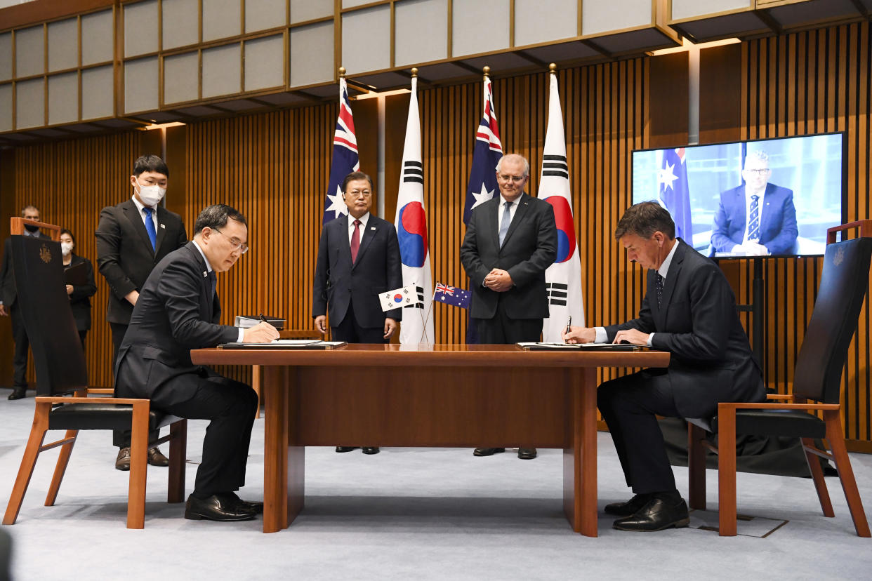 South Korean President Moon Jae-in, center left, and Australian Prime Minister Scott Morrison, second right, witness a signing ceremony with South Korean Trade Minister Yeo Han-koo, second left, and Australian Energy Minister Angus Taylor at Parliament House, in Canberra, Australia, Monday, Dec. 13, 2021. Moon is on a two-day official visit to Australia. (Lukas Coch/Pool Photo via AP)