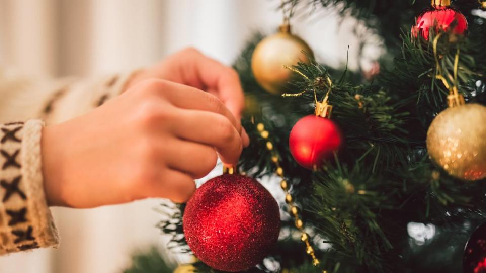 Close-up of a young woman placing baubles on the Christmas tree at home