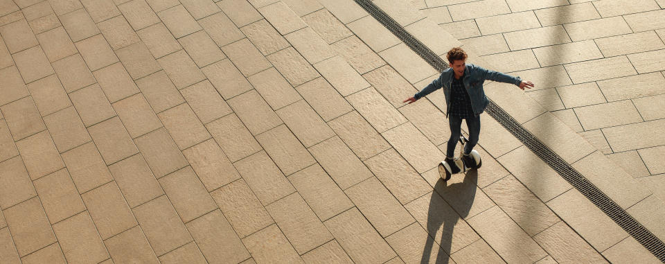 Man riding hoverboard on pavement.