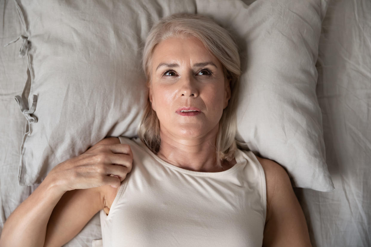 Woman in bed looking hot and uncomfortable in heatwave