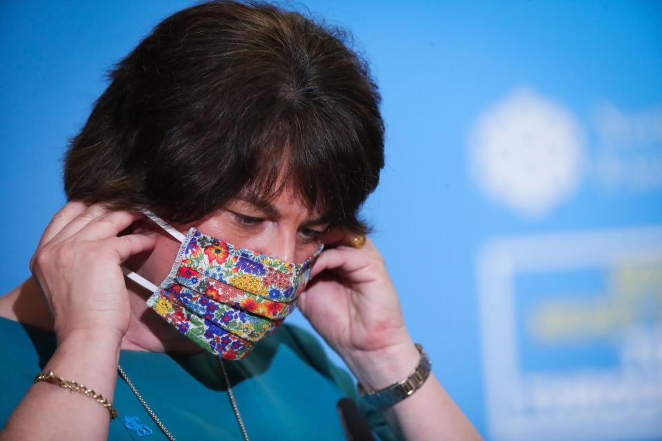 Northern Ireland first minister Arlene Foster removes her face covering before announcing new restrictions (PA)