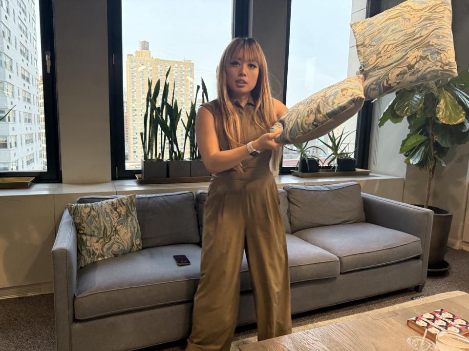 A woman flinging two cushions to her left, in a sample photo demonstrating the iPhone 16 Pro's 48-megapixel Fusion Camera's speed.