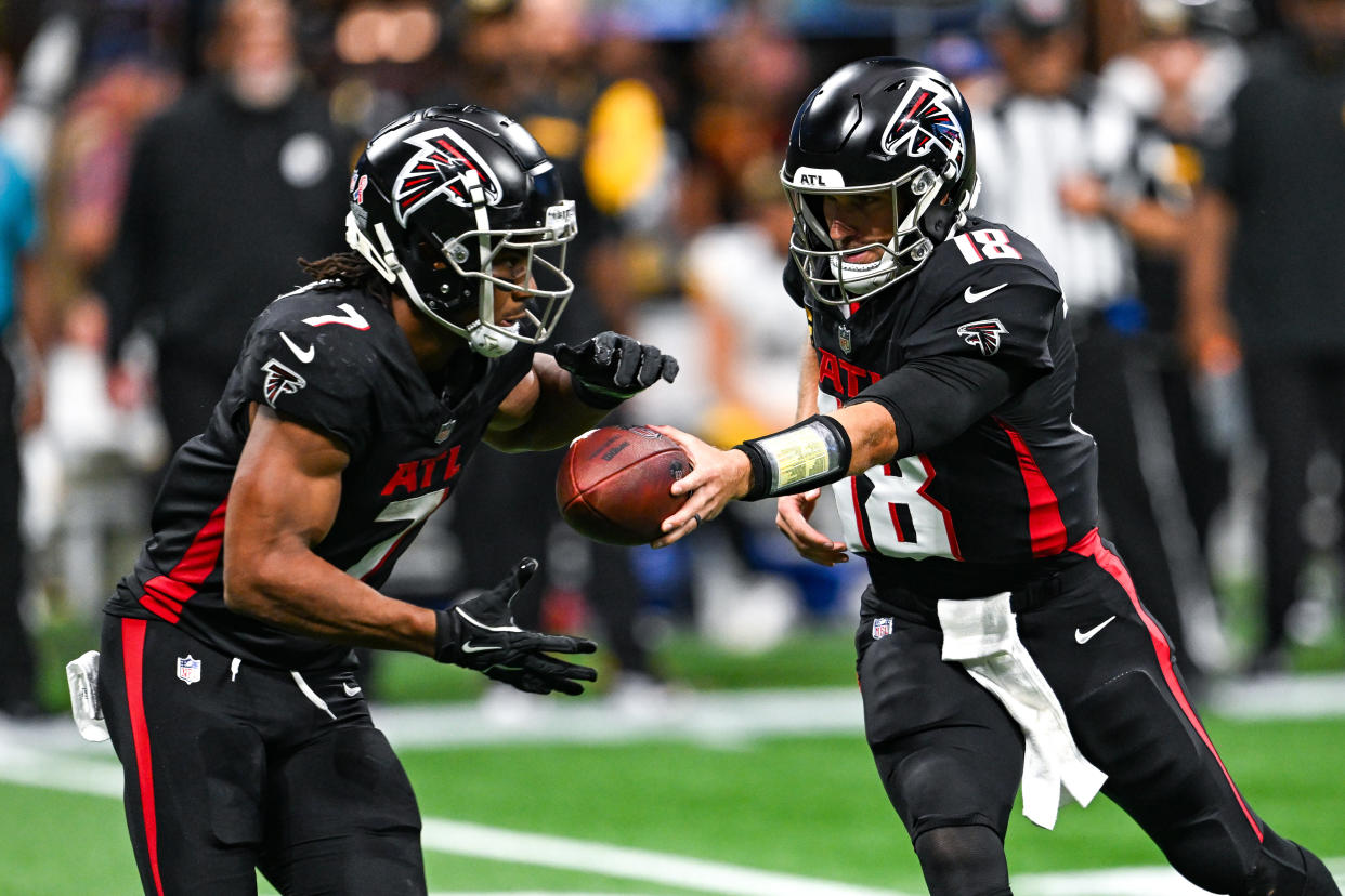 Atlanta quarterback Kirk Cousins (18) hands the ball to running back Bijan Robinson (7) 