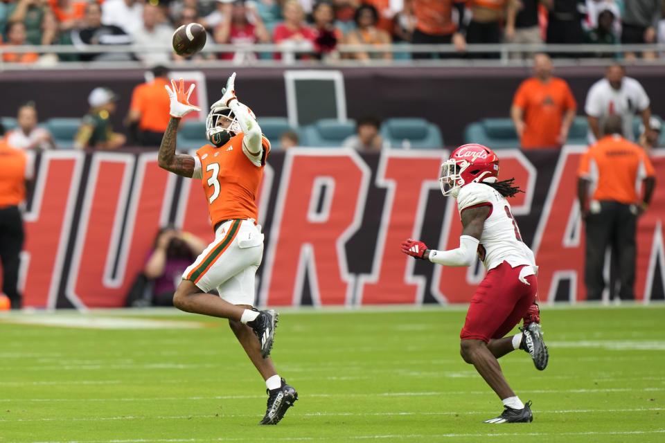 Miami wide receiver Jacolby George (3) catches a pass against Louisville defensive back Trey Franklin (28) during the first half of an NCAA college football game, Saturday, Nov. 18, 2023, in Miami Gardens, Fla. (AP Photo/Wilfredo Lee)