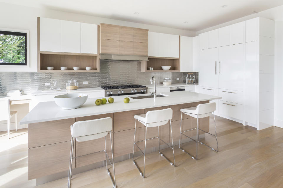 This image released by Bakes & Kropp shows a sleek, modern kitchen combining Bakes & Kropp’s Cucina cabinets in both a high gloss finish and a pearl walnut finish, with a brushed steel and walnut range hood. Along with integrated refrigerators from Sub-Zero, a Wolf range, and quartz countertops, the kitchen is sophisticated, stylish and highly functional. (Brandon C. Tobin/Bakes & Kropp via AP)