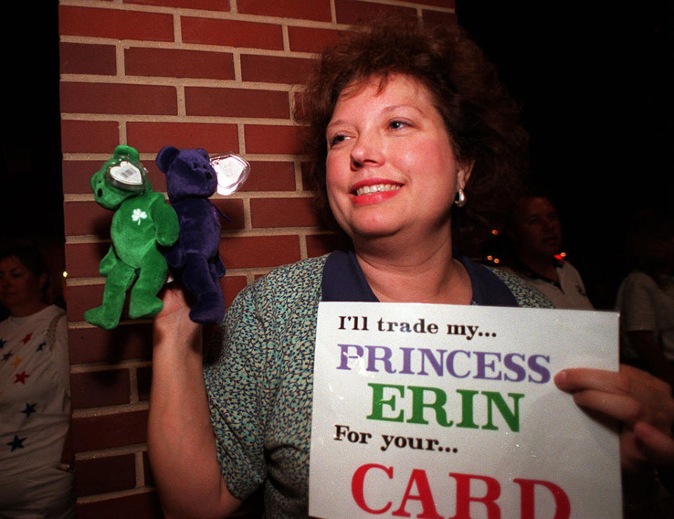 She's holding two beaded stuffed animals and a sign, "I'll trade my Princess Erin for your card"