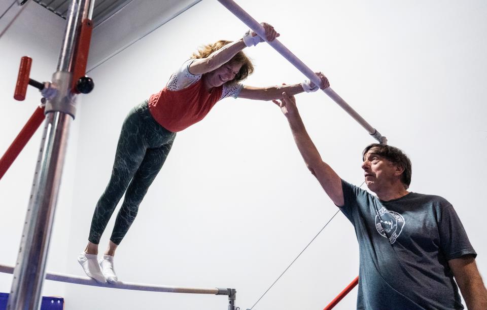 Coach John Wamser spots gymnast Dianne Dagelen as she jumps from the low bar to the high bar at Wildcard Gymnastics in Brookfield, Wis., on Wednesday, July 20, 2022.