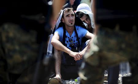 Migrants sitting at the Greek side of the border wait to cross into Macedonia, near Gevgelija August 24, 2015. REUTERS/Ognen Teofilovski