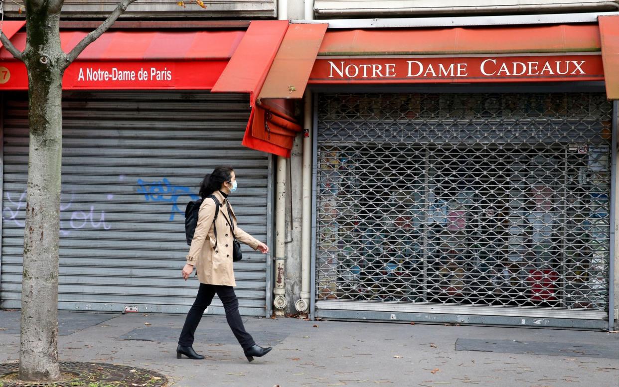 A woman walks past a closed shop in Paris - Chesnot