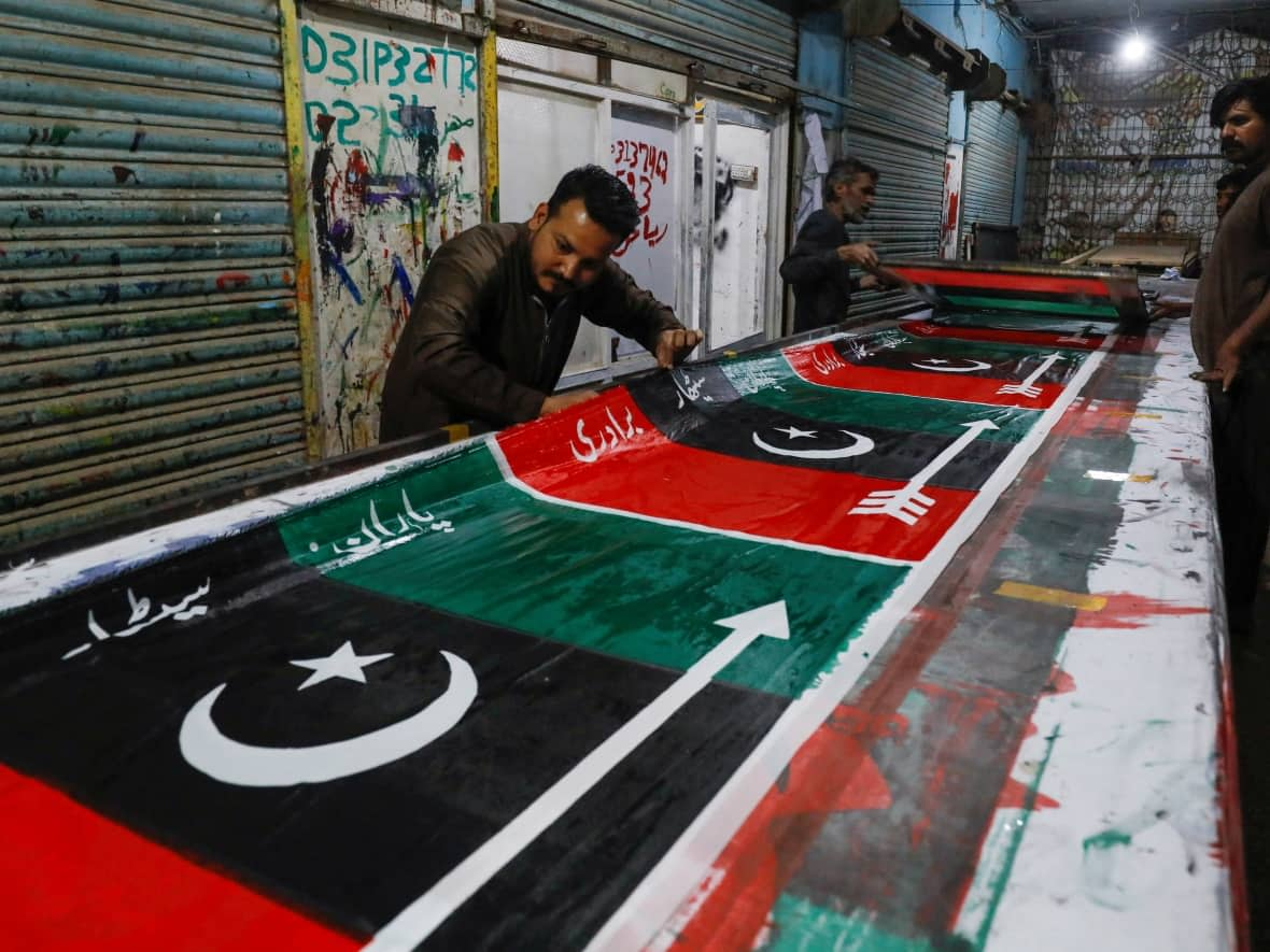 Workers in Karachi, Pakistan, screen-print banners for political party campaigns ahead of general elections, which take place on Thursday.  (Akhtar Soomro/Reuters - image credit)