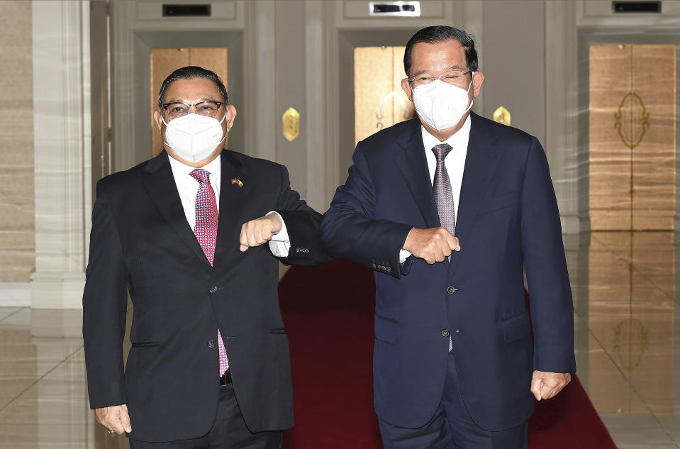 In this photo provided by An Khoun Sam Aun/National Television of Cambodia, Cambodian Prime Minister Hun Sen, right, greets with Myanmar Foreign Minister Wunna Maung Lwin at Peace Palace in Phnom Penh, Cambodia, Tuesday, Dec. 7, 2021. Wunna Maung Lwin is on a two-day official visit to Cambodia. (An Khoun SamAun/National Television of Cambodia via AP)