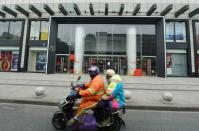 People ride a motorcycle past a closed shopping mall in Hangzhou after the city imposed new measures to prevent and control the new coronavirus