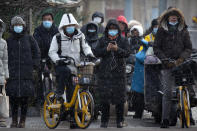 Commuters wearing face masks to protect against the spread of the coronavirus wait at an intersection during a snowy morning in Beijing, Tuesday, Jan. 19, 2021. A Chinese province near Beijing grappling with a spike in coronavirus cases is reinstating tight restrictions on weddings, funerals and other family gatherings, threatening violators with criminal charges. (AP Photo/Mark Schiefelbein)