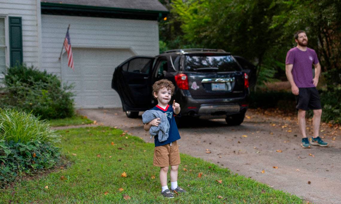 Three-year-old Camden Harrington waves to Raleigh Solid Waste Services employee Alonzo Adams as he makes his rounds Wednesday, July 17, 2024 in Raleigh, N.C.