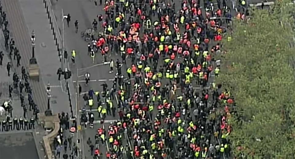 Protesters walk through Melbourne's CBD. Many are seen in high-vis.