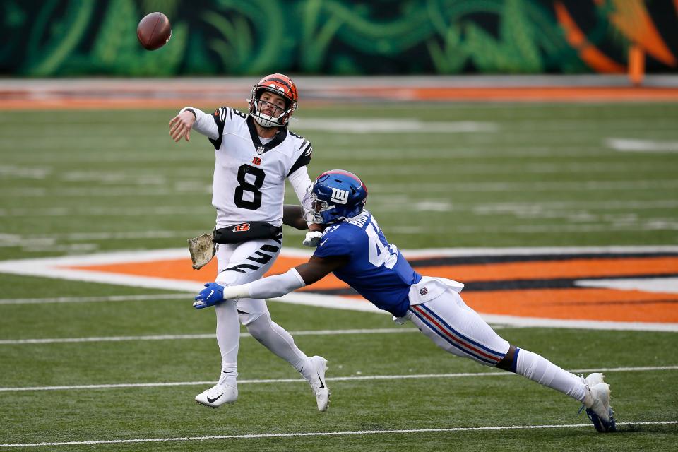 Cincinnati Bengals quarterback Brandon Allen (8) throws the ball away as he's brought down by New York Giants linebacker Cameron Brown (47) in the fourth quarter of the NFL Week 12 game between the Cincinnati Bengals and the New York Giants at Paul Brown Stadium in Cincinnati on Sunday, Nov. 29, 2020. A late fumble sealed the Bengals 19-17 loss to the Giants.