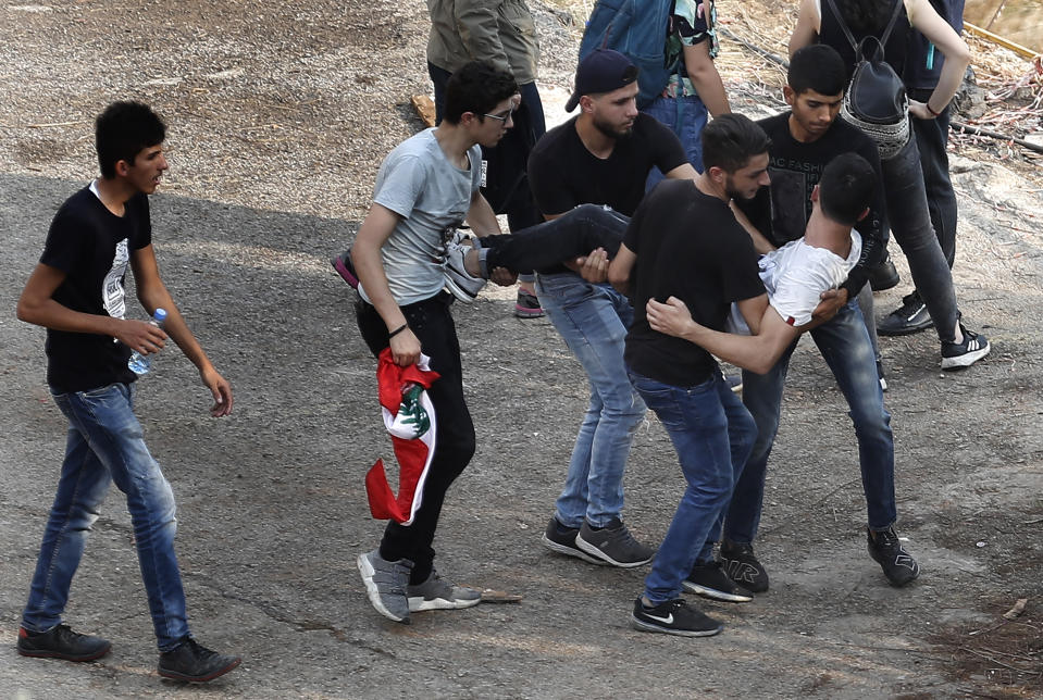 An injured protester carried by his friends after a clashes erupted between pro-Hezbollah and anti-government protesters near the government palace, in downtown Beirut, Lebanon, Friday, Oct. 25, 2019. Hundreds of Lebanese protesters set up tents, blocking traffic in main thoroughfares and sleeping in public squares on Friday to enforce a civil disobedience campaign and keep up the pressure on the government to step down. (AP Photo/Hussein Malla)