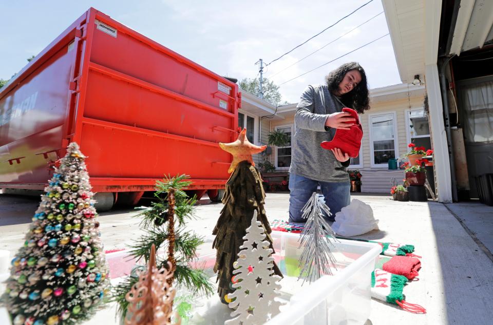 Isaac Moscinski lays out Christmas items to dry at the home of his grandparents Dave and Shari Moscinski Monday, July 8, 2024, in Appleton, Wisconsin. Some Appleton residents, including the Moscinski family who lives along N. Viola St., experienced flash flooding July 5. At right is Moscinski’s grandson Isaac Moscinski.