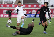 Canada's Kamal Miller, bottom left, tackles United States' Sergino Dest (2) as Canada's Tajon Buchanan (11) looks on during the first half of a World Cup soccer qualifier in Hamilton, Ontario, Sunday, Jan. 30, 2022. (Frank Gunn/The Canadian Press via AP)