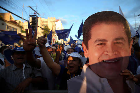 A supporter of President and National Party presidential candidate Juan Orlando Hernandez holds an image of Hernandez as she waits for official presidential election results in Tegucigalpa, Honduras, November 28, 2017. REUTERS/Edgard Garrido