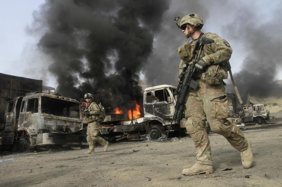 NATO troops walk near burning NATO supply trucks after, what police officials say, was an attack by militants in the Torkham area near the Pakistani-Afghan in Nangarhar Province June 19, 2014. (REUTERS/ Parwiz)