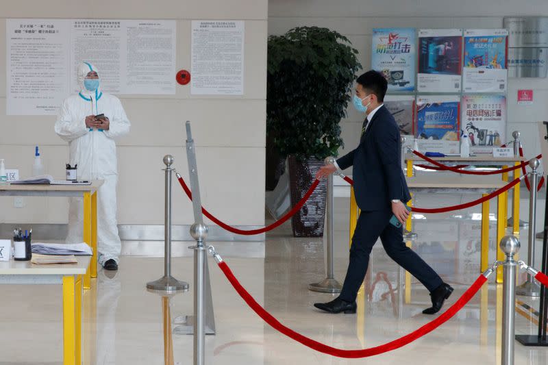 A worker wears a protective suit as a businessman enters an office building in Beijing as the country is hit by an outbreak of the novel coronavirus