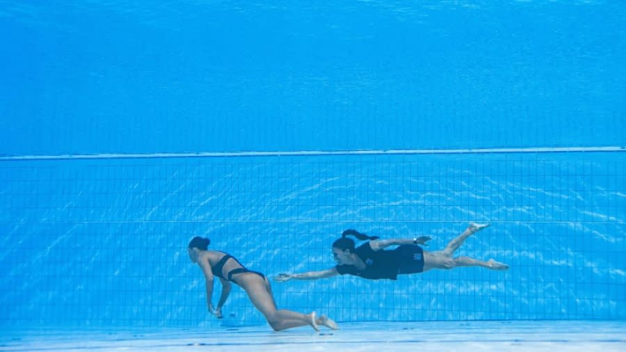 Anita Alvarez is retrieved from the pool by coach Andrea Fuentes during the 2022 FINA World Championships. (Oli Scarff/AFP via Getty Images)